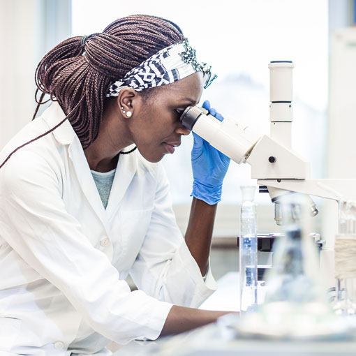 woman in lab looking using microscope