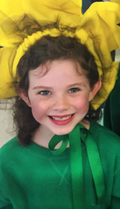 A young girl dressed as a daffodil smiles 