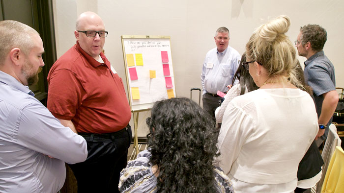 Participants at Collaborative gather around a white board for discussions