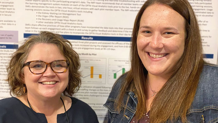 Heather Marshall and Amanda Young, smiling, standing in front of poster detailing improvement project