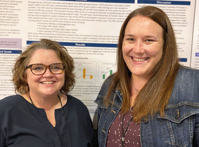 Heather Marshall and Amanda Young, smiling, standing in front of poster detailing improvement project