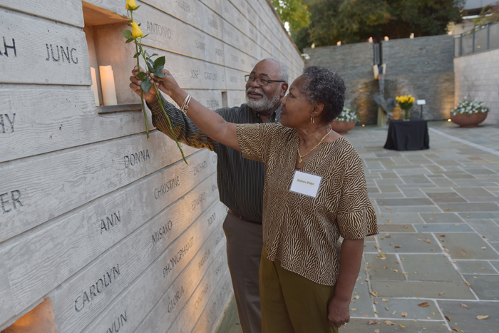 Couple placing yellow roses in National Donor Memorial wall of names