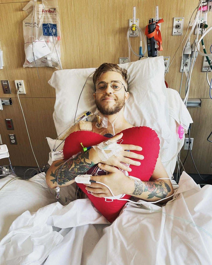 Randall in hospital bed, hugging a heart-shaped red pillow