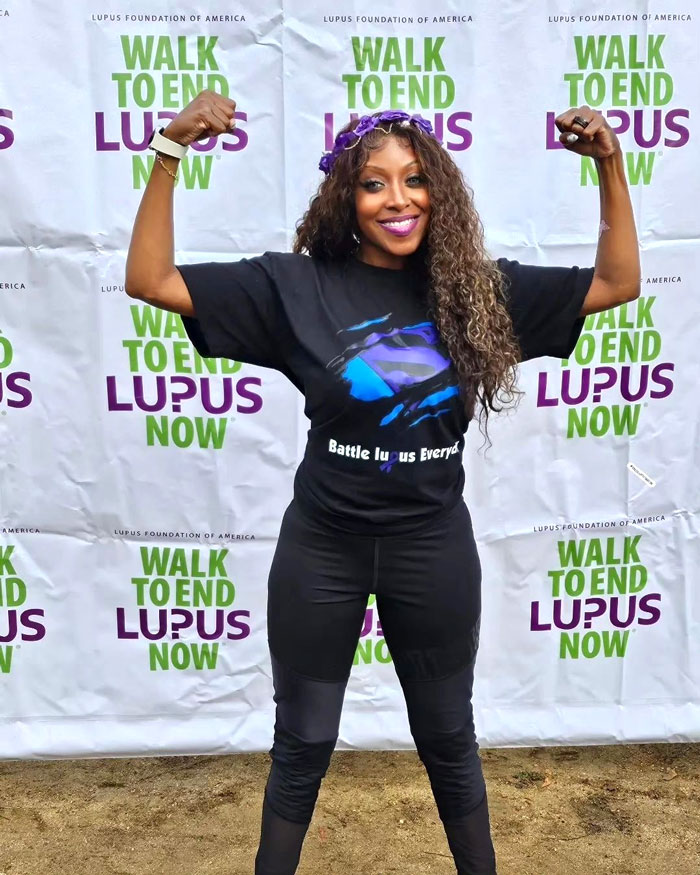 Shamekka flexing in front of Lupus Foundation of America banner