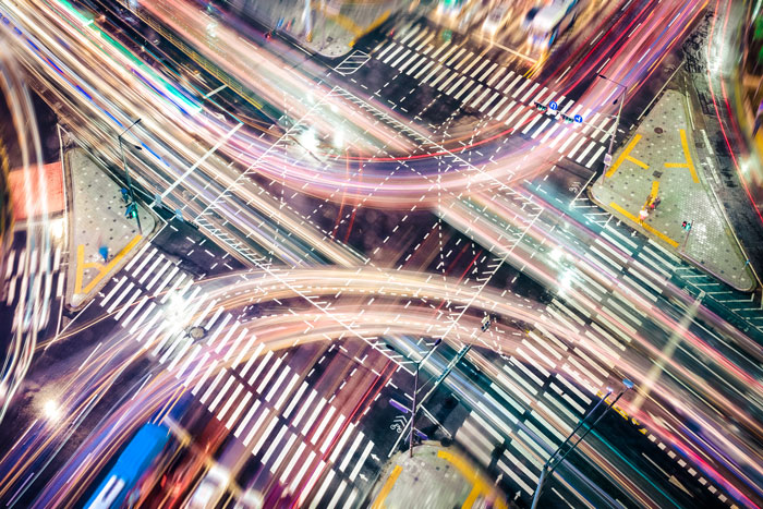 Overhead view of busy nighttime intersection with blurred lights of moving vehicles