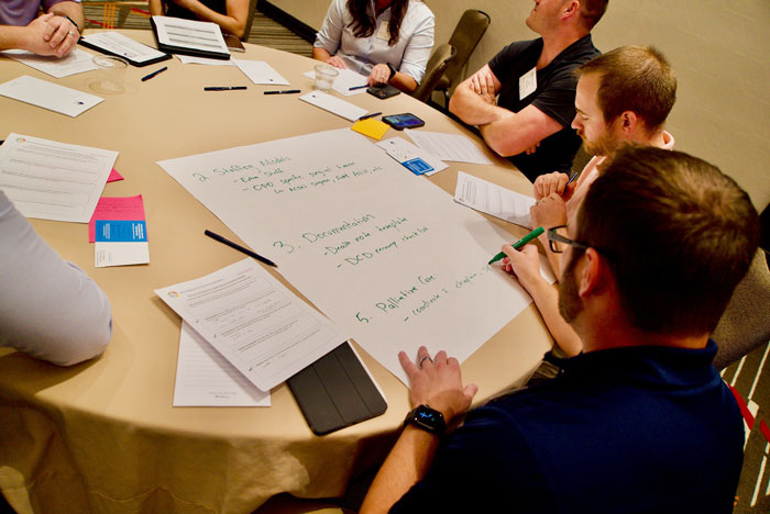 Small group meeting during OPTN DCD Procurement Collaborative, showing one individual writing on large sheet of paper