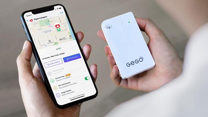 organ-tracking-gego-device Hands holding an iphone with screen displaying map with location indicator, next to a white GEGO tracking device