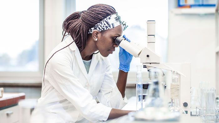 woman in lab looking using microscope